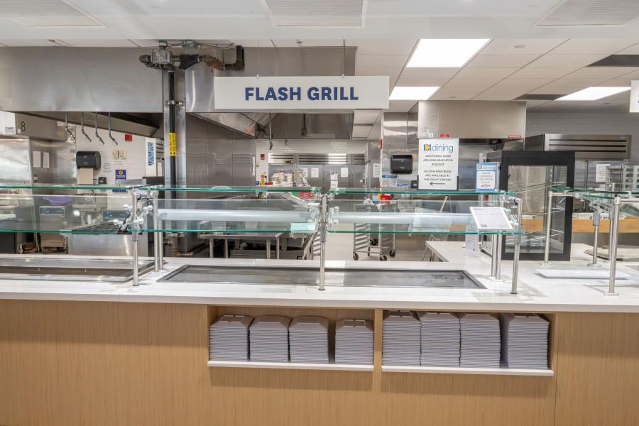 Front view of DI Dining's "Flash Grill" area, including prep counters and stacks of plates