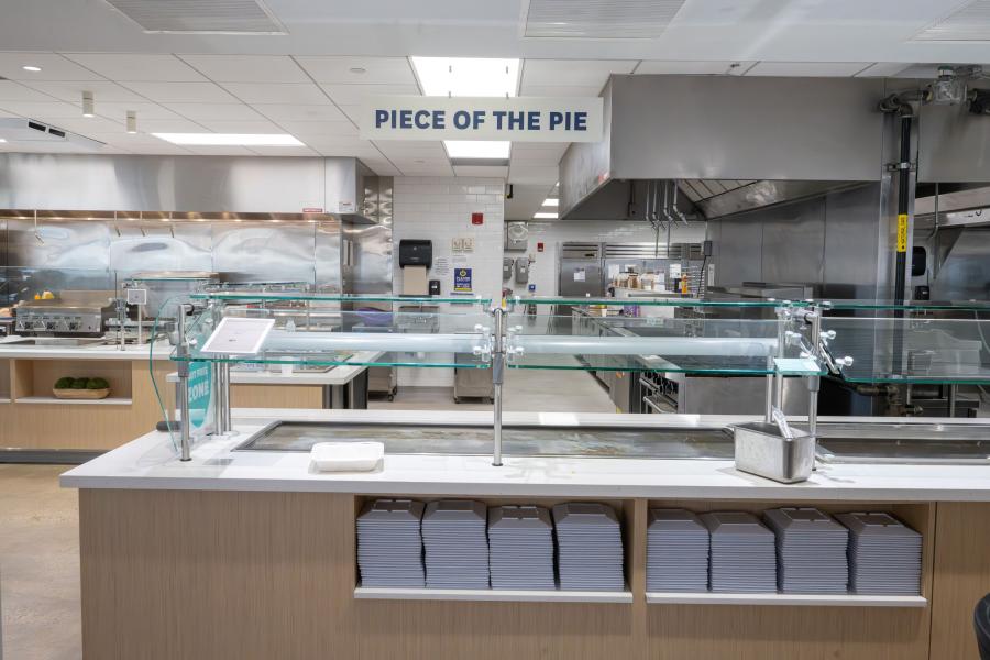 Front view of DI Dining's "Piece of the Pie" area, including a prep counter and stacks of plates
