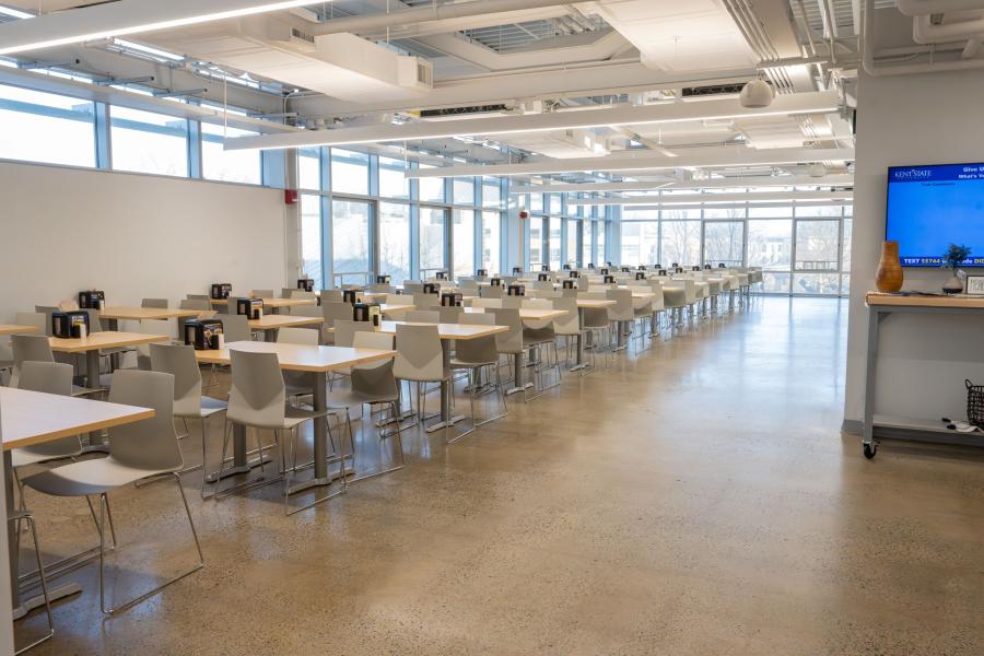 A large seating area within DI Dining, featuring three long rows of tables and a wall of windows