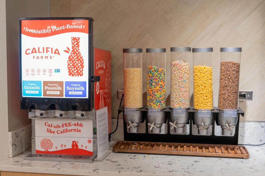 Close up of a cereal station at Eastway Dining Hall, including 5 dispensers, each with a different type of cereal, and a milk dispensing-machine with oatmilk, peamilk, and soymilk options