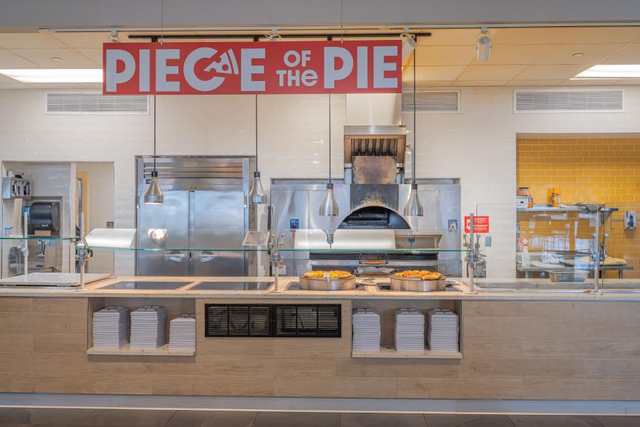 View of Eastway's "Piece of the Pie" area, including a pizza oven, a prep counter, and stacks of plates