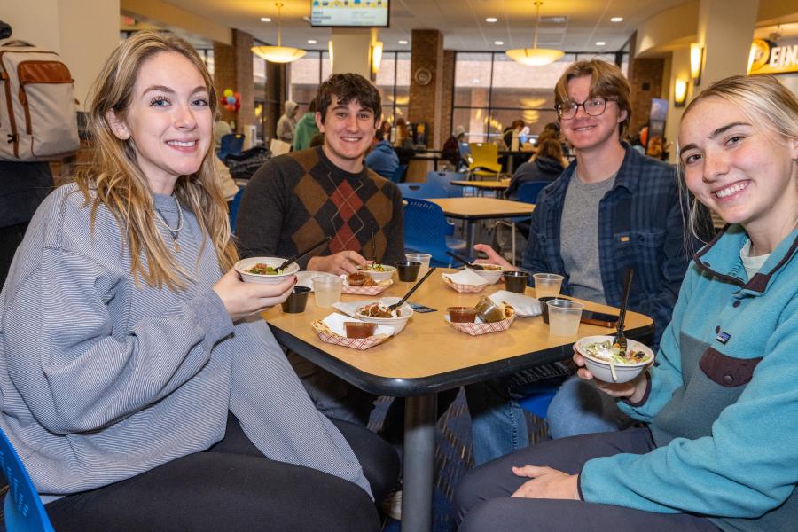 A group of students smiling and enjoying free food samples