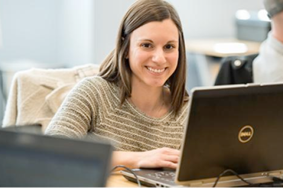 A smiling program participant works on her computer.