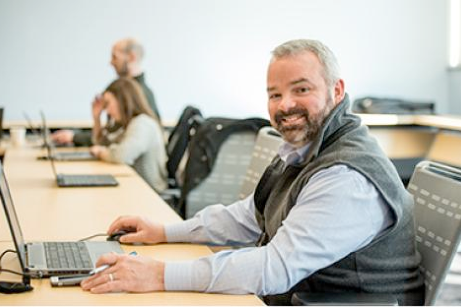 A smiling program participant works on a laptop
