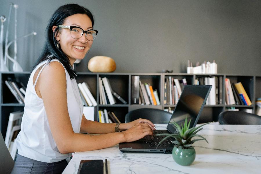 A smiling woman types on her computer.