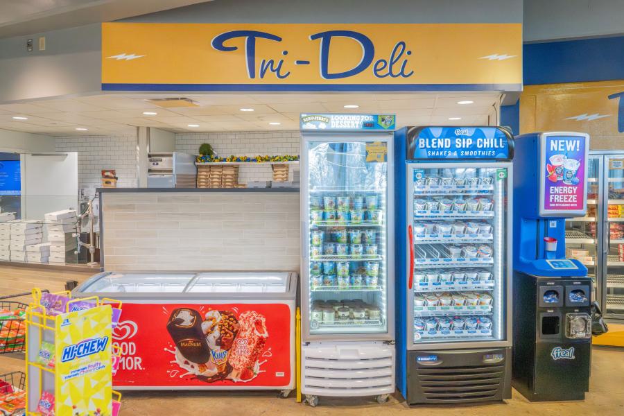 Tri Deli logo above several to-go snack options displayed in freezers and coolers