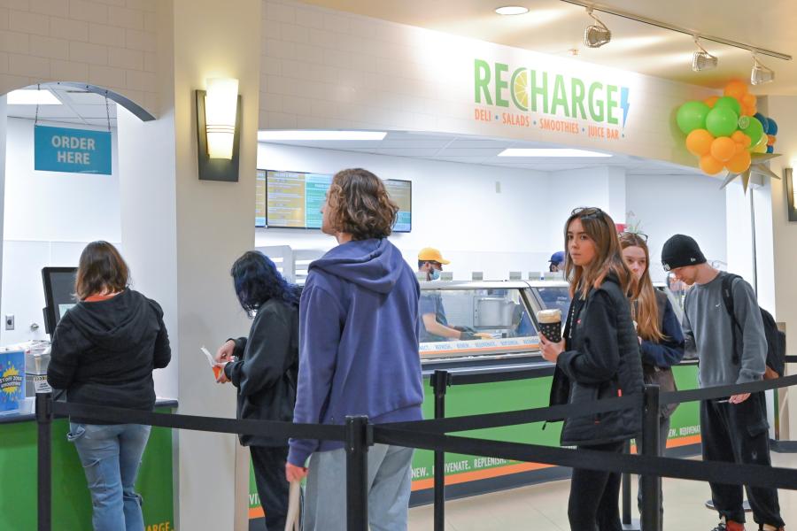 Students in line for Recharge, with Recharge logo visible on the wall above the counter