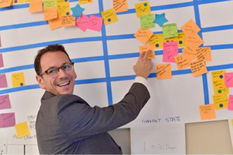 A smiling program participant places a sticky note on a board