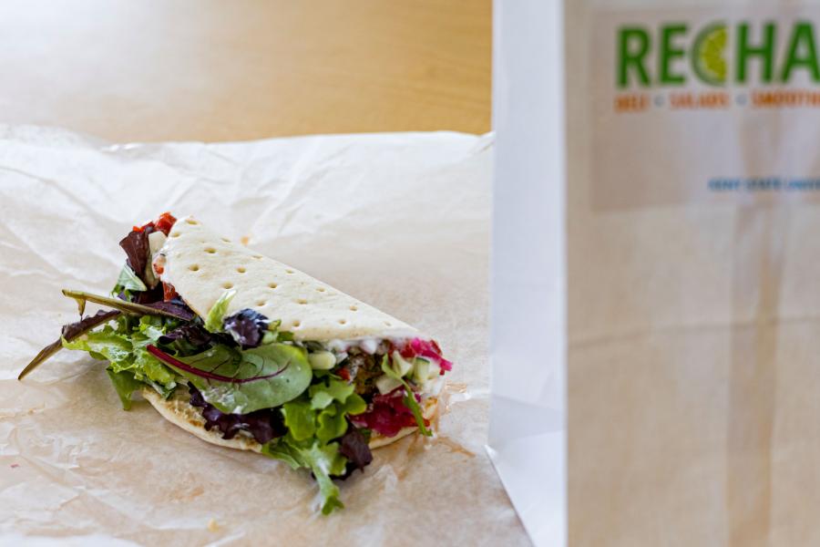The Veggie Pita from Recharge sitting on a table next to a Recharge take-out bag