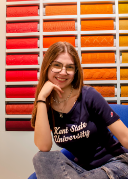 Adelynn Prushing posing for photo in front of colorful fabric background. 