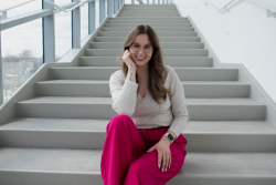 Headshot of Allie Adler sitting on a light gray staircase