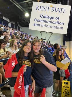 Brittany Lucia with a Kent State College of Communication and Information sign