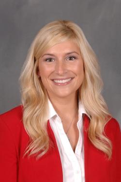 Katie Schalmo smiling. She has blonde hair and is wearing a red jacket.