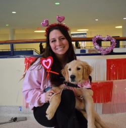 Melissa Williams posing for a photo while holding a puppy. 