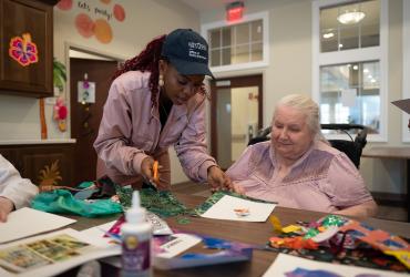 Adedayo Adeagbo (left) volunteering to help older adults at the Tamarack Ridge facility