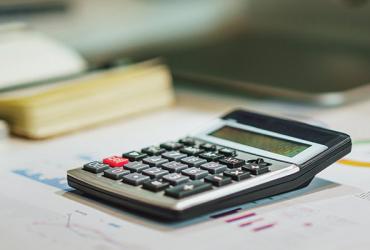 A calculator sits on a desk next to a keyboard.