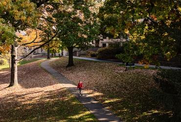 A Kent State student walks through fallen leaves on Front Campus