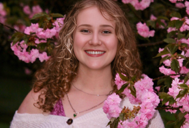 Madelyn Lands surrounded by pink flowers.