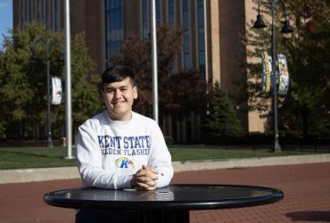 Asadbek Masharipov sitting at a table outside on the Kent State campus. 