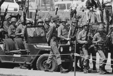 National Guard personnel walk with weapons and jeeps in a line on May 4, 1970, at Kent State University. (Photo credit: News Service May 4 photographs, Kent State University Libraries, Special Collections and Archives)