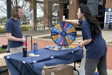A student spins a prize wheel at a table during Thank-A-Giver Day for Flashes Give Back Week