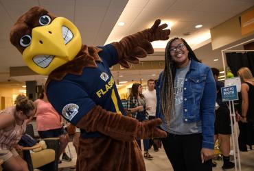 Flash poses for a picture with a student.