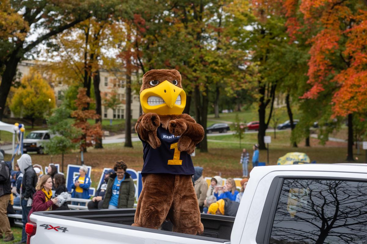 Kent State University’s mascot, Flash, standing in the back of a white pickup truck during the homecoming parade, pointing directly at the camera.