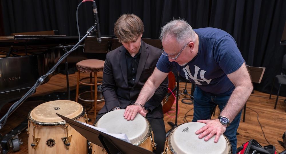 Bobby Sanabria teaches a student to play congas