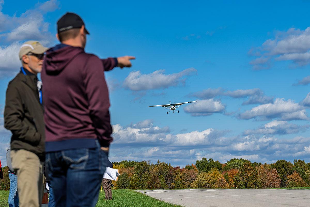 An observer points to an airplane in the sky approaching for a landing