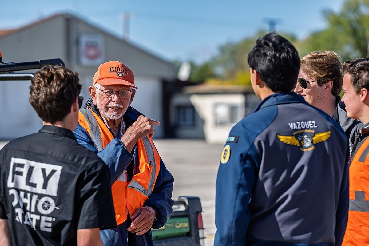 A judge in conversation with several student pilots