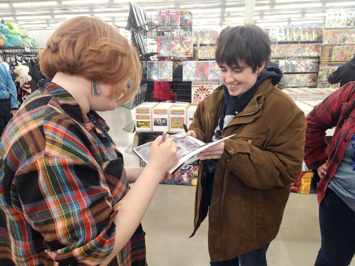 Emma Patchin signs a copy of "Flash Fiction" for a fan at Akron ComicCon