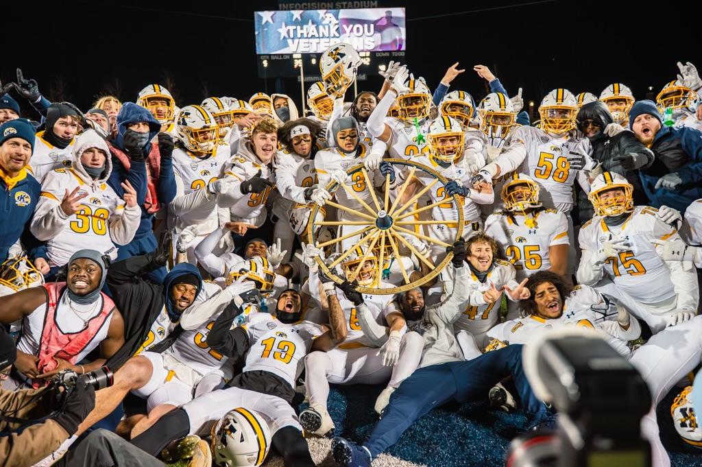 The Kent State football team holds the Wagon Wheel in celebration after beating the University of Akron. 