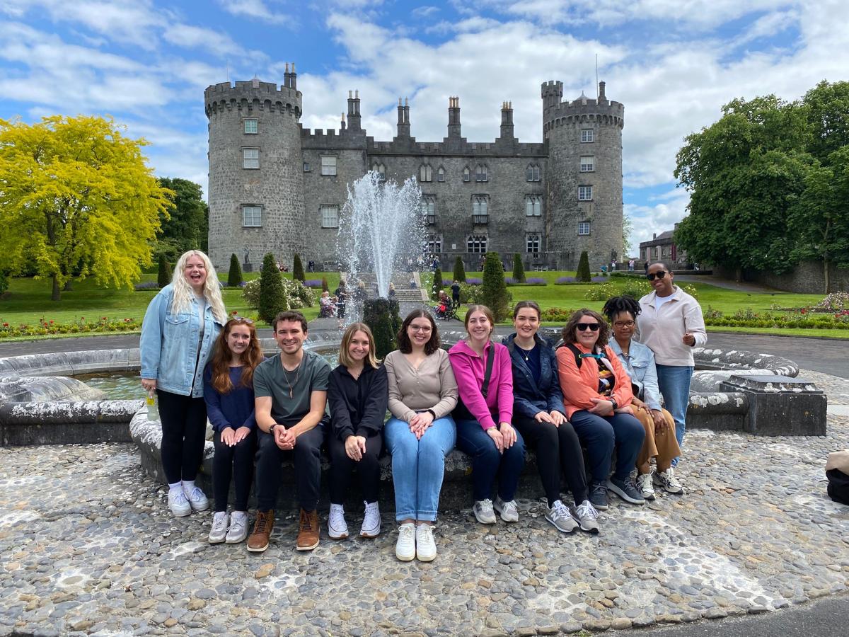 Group photo of students sitting in front of a castle in Ireland.