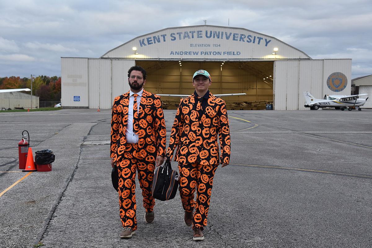 Two pilots dressed in halloween garb with jack-o-lantern-printed suits.