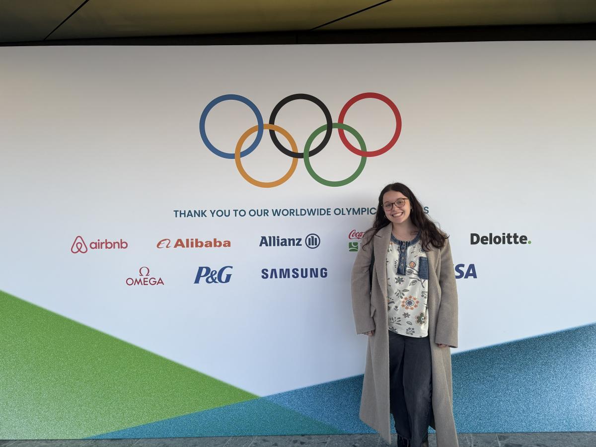 Alex Newnes standing near an Olympic wall. 