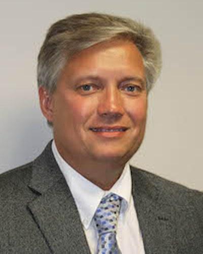 Head-and-shoulders portrait of a man facing the camera with a studio-style backdrop.