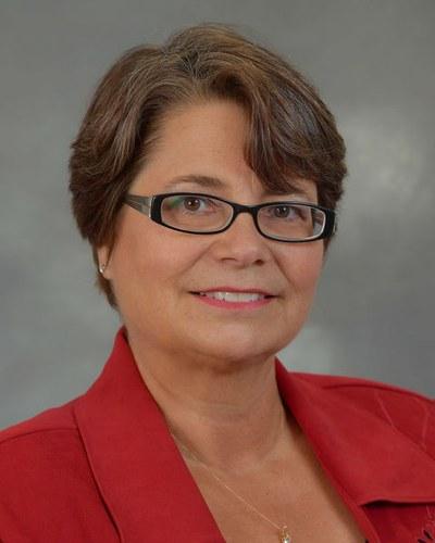 Professional headshot of a woman in business-casual attire against a neutral background.