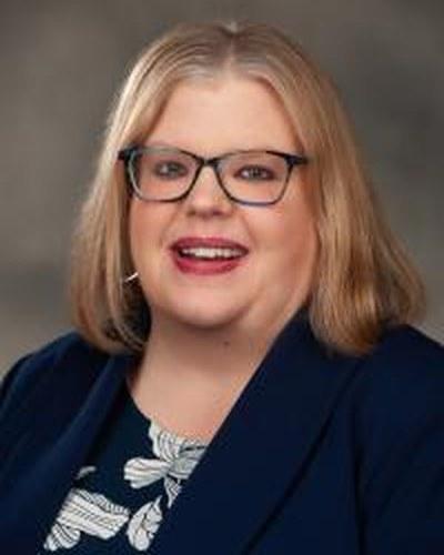Professional headshot of a woman facing the camera against a solid-colored backdrop.