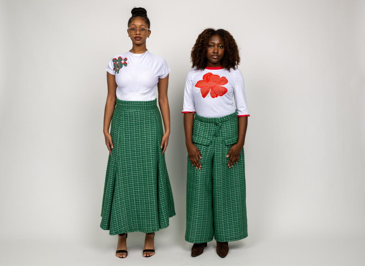 two models wear green tweed pants and skirts along with white tops featuring singular floral prints