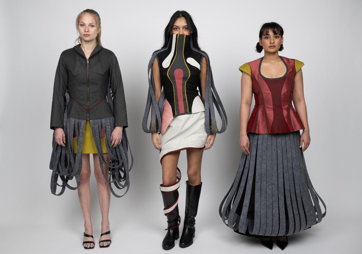 three models show off student designs featuring abstract skirts and dresses