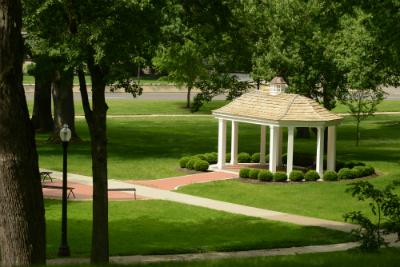 White gazebo in a beautiful treed setting and walkway