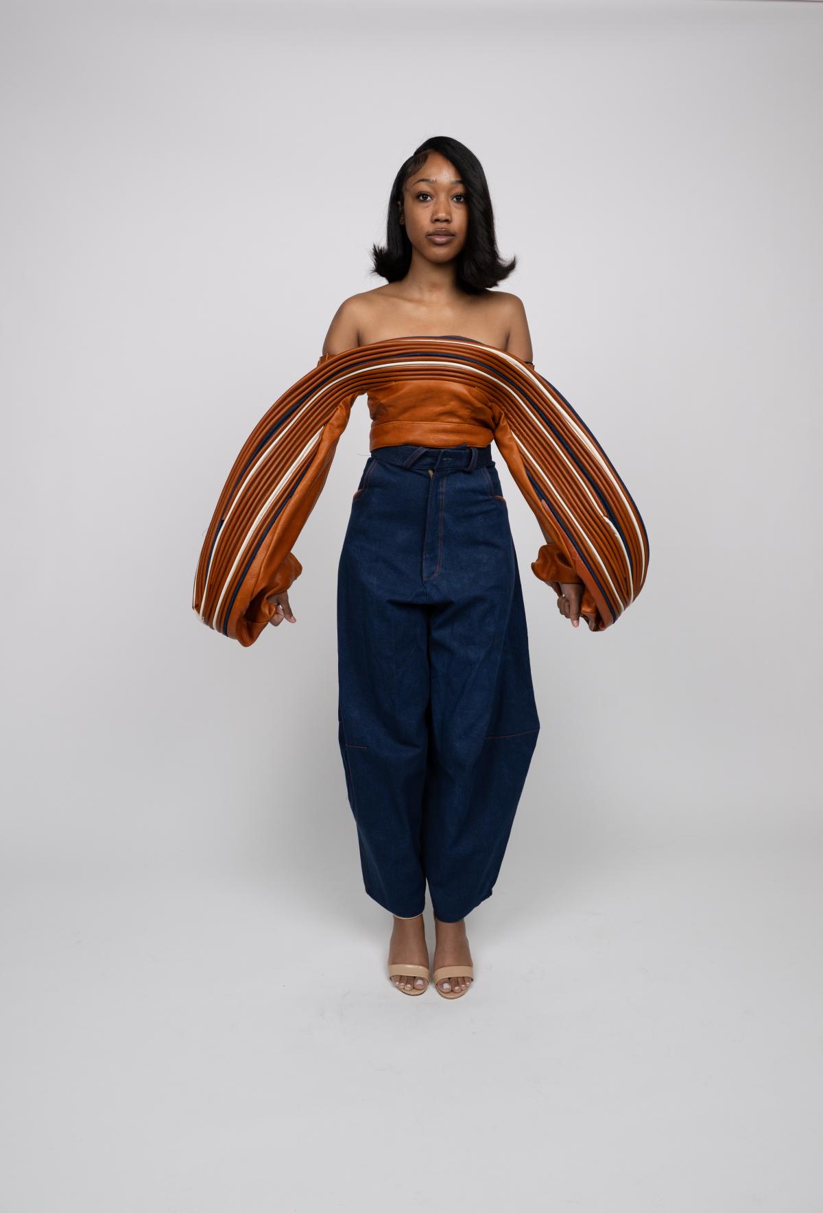 a models wears barrel jeans and an orange top with extreme off-the-shoulder sleeves