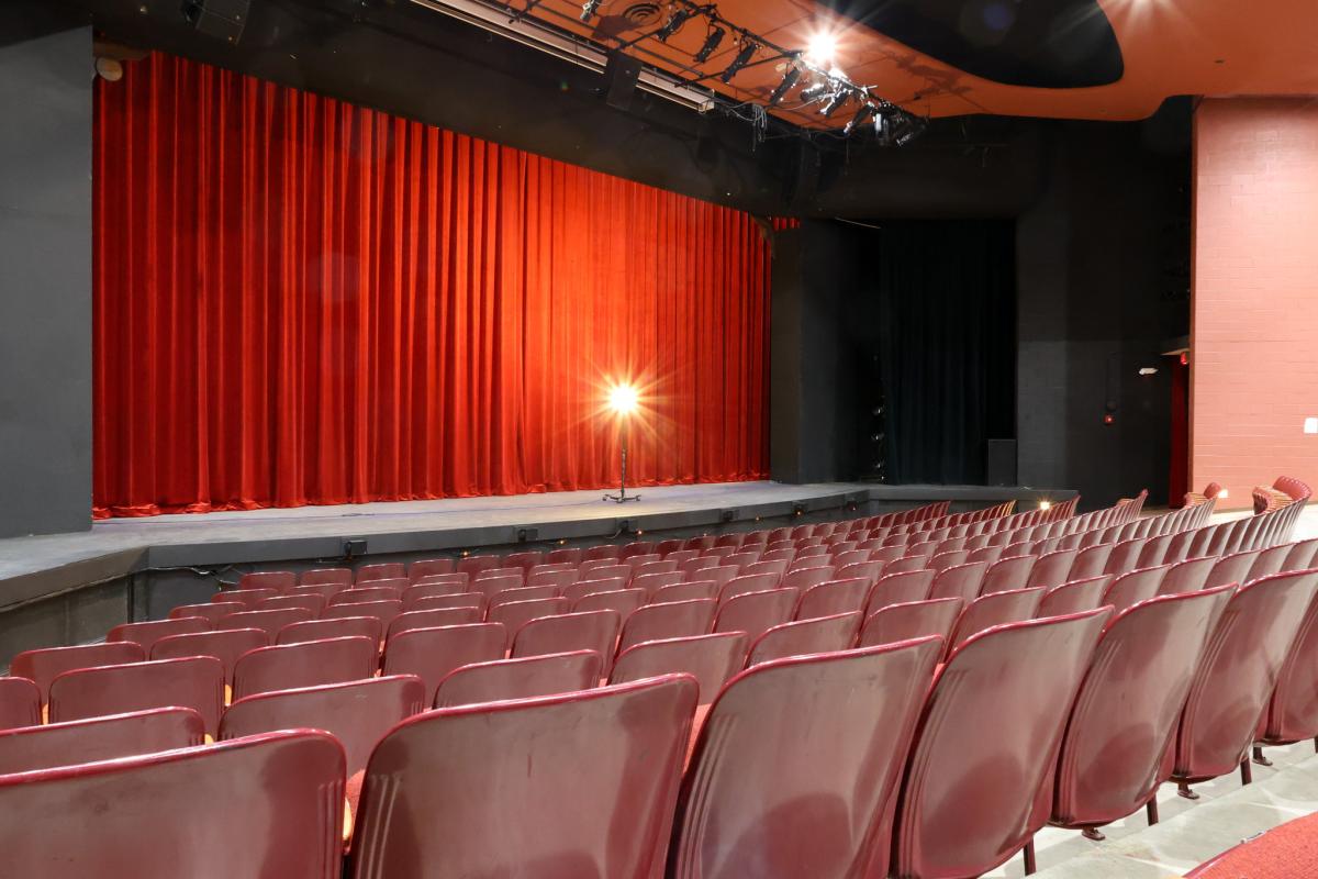 Empty seats lead to a stage with a light on