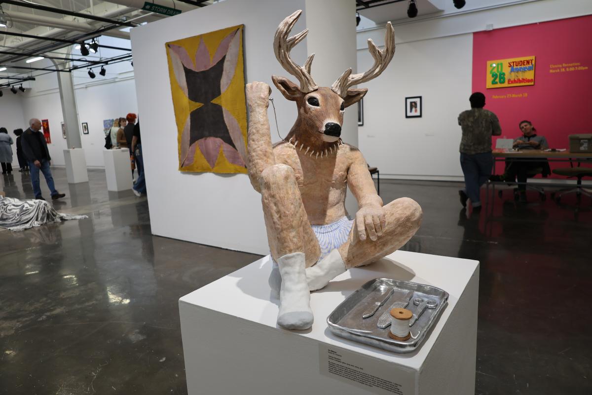 Ceramics statue featuring deer head on human body, sitting with one knee propped up