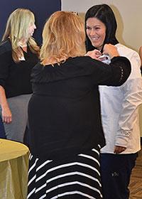 Angela Douglass, ADN senior lecturer, presents a pin to Manda Adkins who was the first ADN student to receive a white coat at 鶹Ƶȫ.