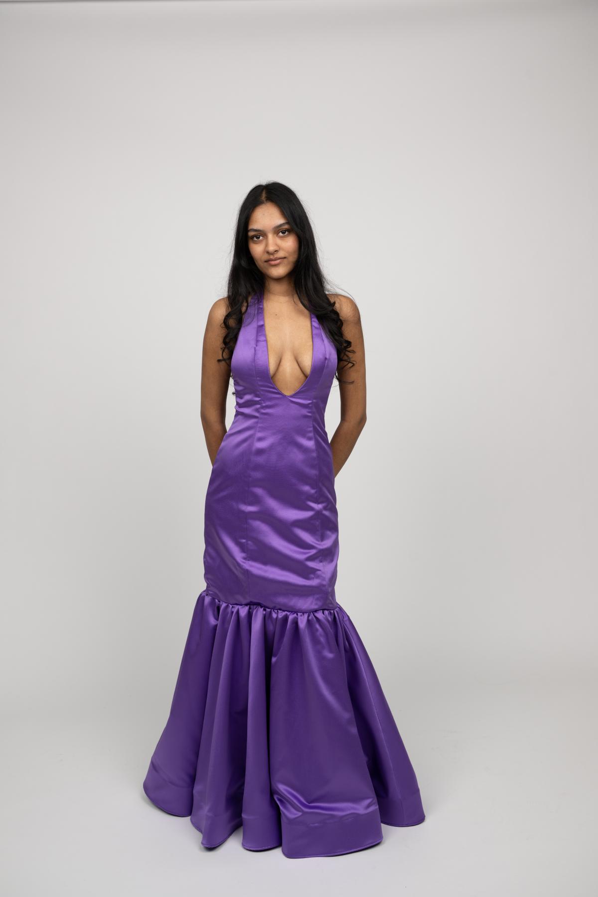 a model wears a vibrant purple mermaid-shaped gown with a plunging neckline