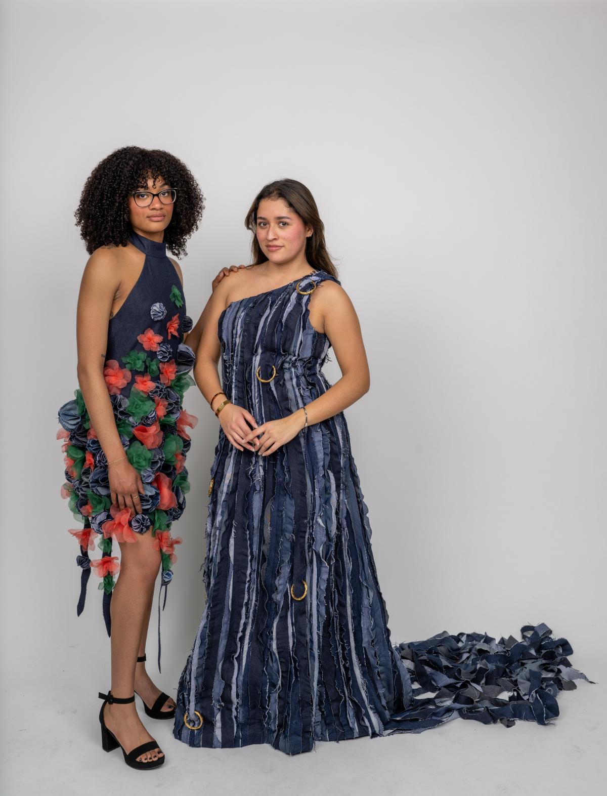 two models wear custom denim dresses, one is a midi halter dress with 3d floral appliques the other is a floor length gown with a train 
