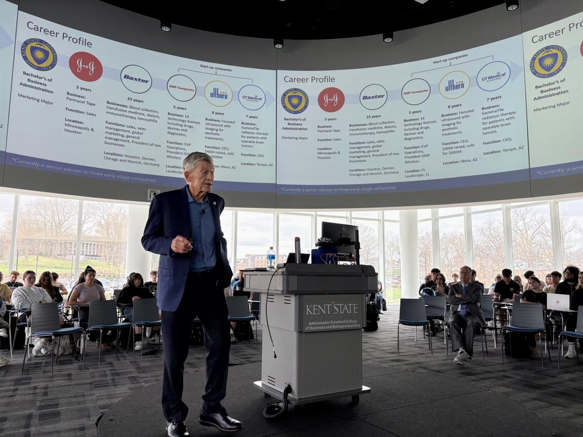 Likens with career profile on screen behind him