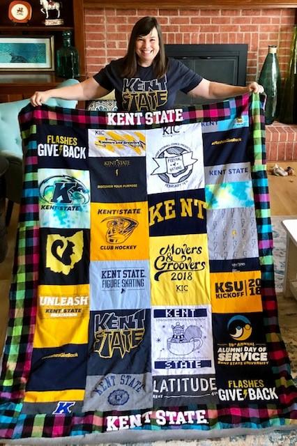 Photo of alumna holding up handmade Kent State quilt