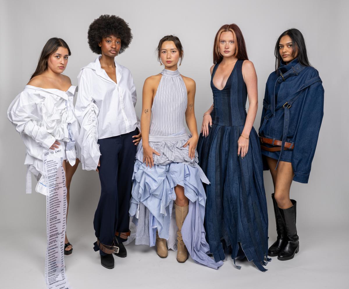 five models wear various pieces of a collection. one model wears an avantgarde whit dress with a long piece of fabric dangling down the front resembling a receipt another wears a light blue dress with a slit up and tiered ruffles. two wear denim dresses, with one style like a suit jacket